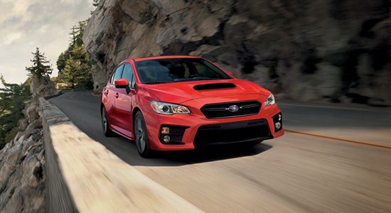 The Subaru WRX in Red driving on a road.